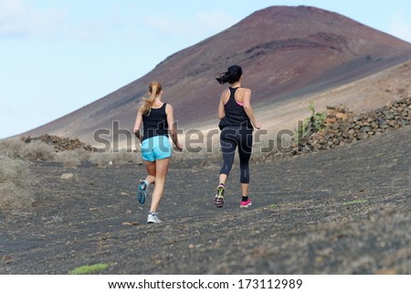 Two female running athletes. Women trail runner sprinting for success goals and healthy lifestyle in amazing nature landscape.