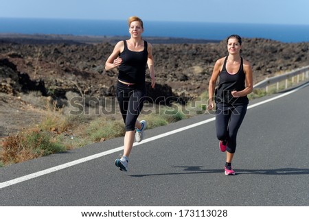 Two Runner women running on mountain road in beautiful nature, volcanic landscape on Canary islands