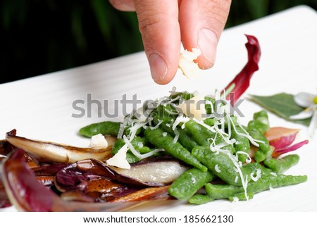 Closeup of chef adding finishing touch on his dish before it goes on the table / fine dining
