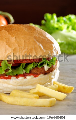 Big vegetarian burger with lettuce, tomato and cucumber accompanied by French fries (Selective Focus, Focus on the front of the lettuce, lentil burger, tomato and sauces)