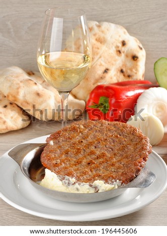 Presliced traditional burger patty called pljeskavica, served with pita bread with some cream cheese Kajmak. Balkan food