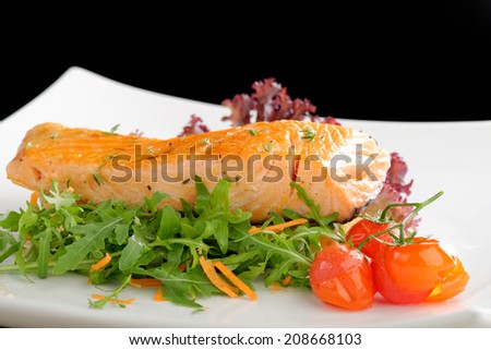 Healthy fish cuisine : baked pink salmon steaks garnished with tomatoes and rocula on white dish
