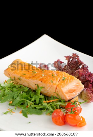 Healthy fish cuisine : baked pink salmon steaks garnished with tomatoes and rocula on white dish