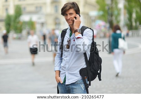 Student with the mobile smart phone walking, background is blurred city