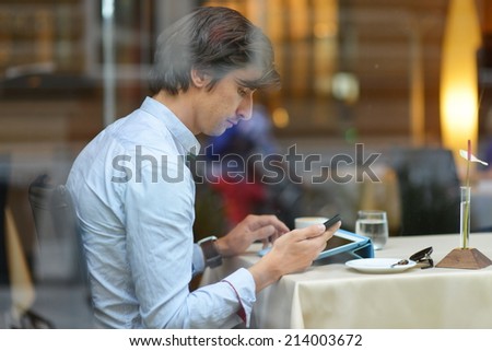 Young fashion man / hipster drinking espresso coffee in the city cafe during lunch time and working on tablet computer