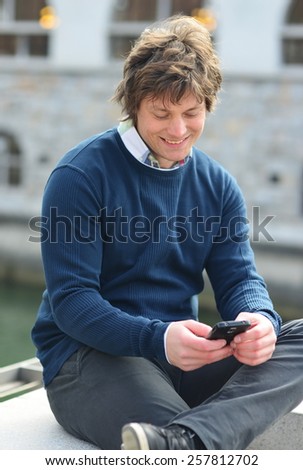 Portrait of young guy sending message with smartphone