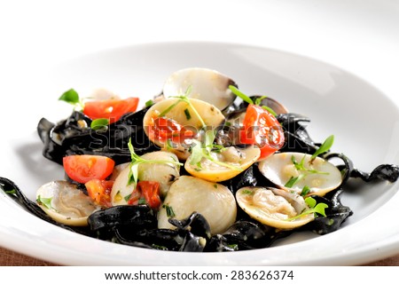Close-up of squid ink colored tagliatelle with sliced octopus and vongole mussels