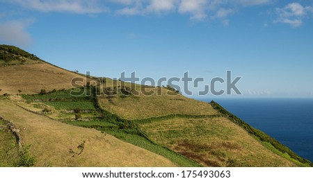 Green hills above the ocean with blue sky in the background