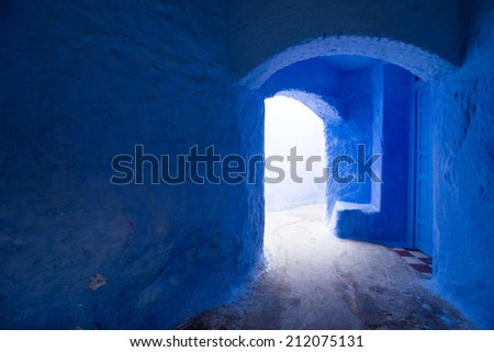 Light at the end of narrow street surrounded with blue arch walls