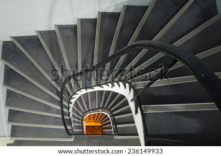 Spiral staircase with warm orange light at the end