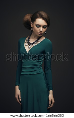 Girl with beautiful hair and makeup in a green evening dress. Evening makeup. Jewelry