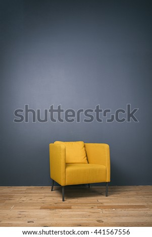 Studio shot of modern yellow arm-chair against of grey wall.Copy space.