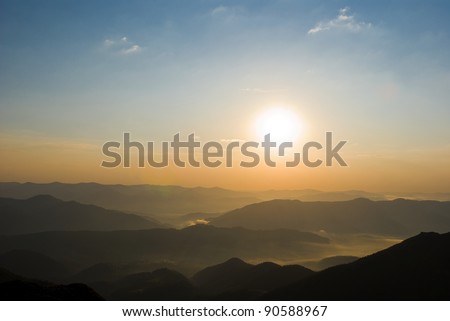 sun rising above a green hills