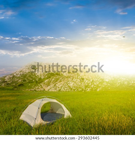 white touristic tent in a green hills at the sunrise