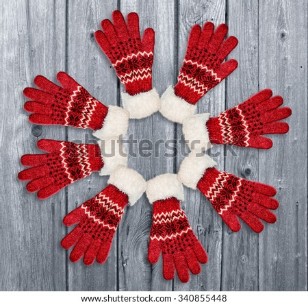 Ornament with red gloves on wooden background. Christmas, winter decorative motif