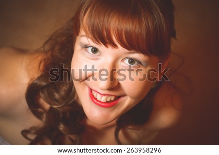 Portrait of a glamorous girl with long dark hair. The girl is very surprised. Eyes wide open. The view from the top. Photo taken in the studio. Caucasian.