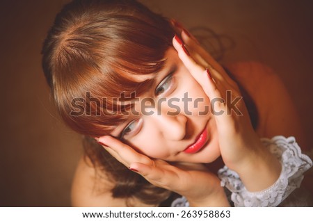 Portrait of the lovely sad girl with long dark hair. Palms of hands clasped the girl\'s head. The view from the top. Girl in white lace underwear. Photo taken in the studio. Caucasian.