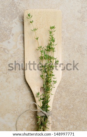 fresh picked organic Thyme tied to wooden spatula with hemp twine rope on tan kitchen counter top cooking with herbs