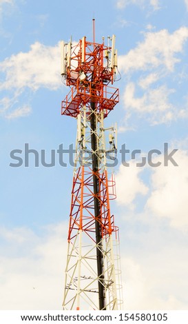 red and white tower of communications or mobile phone with a lot of different antennas under clear sky