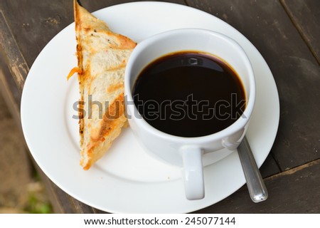 cup of coffee and sandwich on wooden table in coffee shop