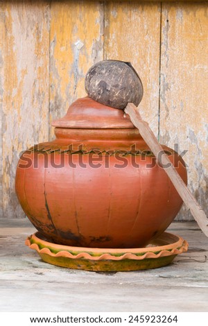 thai clay water pot with dipper made from coconut shell on wooden shelf