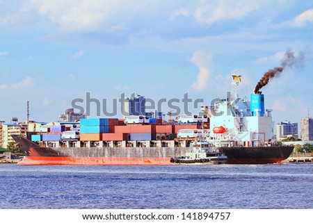 Large container cargo ship and support tug boat