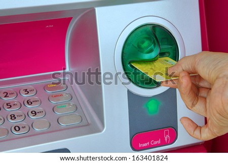 Lady hand inserting card into an pink ATM to begin a financial transaction