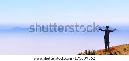 young Businessman standing on top of mountain