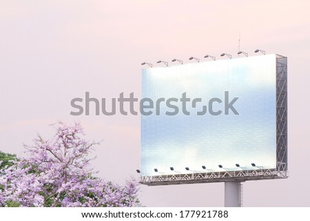 blank white billboard on the edge of country road sunset pink sky with spot light and pink flower tree.