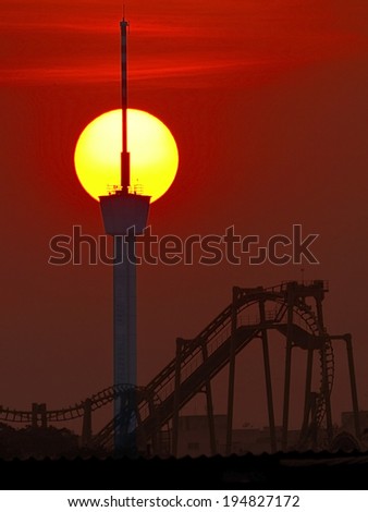 silhouette of a roller coaster at sunset, after a sunny day at entertainment park