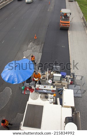Workers making asphalt with shovels at road construction and Road rollers during asphalt paving works for repairing blacktopping transportation street.