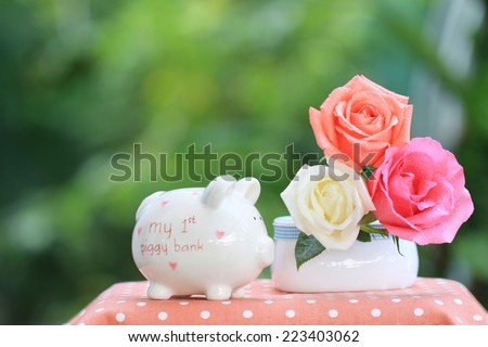 Piggy banks for creating the habit of saving money for kids with beautiful colored red white and orange roses with free space for text valentine green background