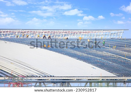 Workers wear safety equipment to Working at Heights on a high roof, large plants. Built with a steel rod and sheet aluminum is strong, modern design. under blue sky and cloud space.