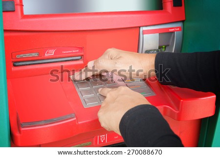 Hands of women are pressing the button code of Key word with protection guard by cover hand at Automated Teller Machine for get money.