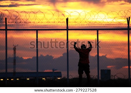 Middle-aged men stand rail, steel mesh and barbed wire at sunset. The concept of restricted freedom of independence.