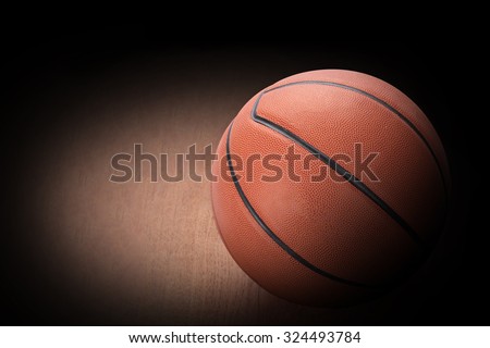 Basketball on hard wood dark background as a symbol of sport and exercise, leisure activities, team players with dribbling and passing the ball in a competitive match. This has clipping path.