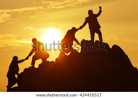 Silhouette of the man Bring hand up a friend to top the peak of mountain on sunrise sky , Business success goal together, Conceptual design.