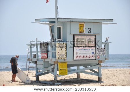 LOS ANGELES - MAY 11: Life Guard Tower under the blue sky in Malibu Beach with man preparing his surf board on May 11, 2012 in Los Angeles, California.