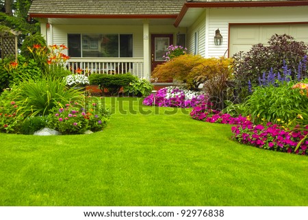 Manicured House And Garden Displaying Annual And Perennial Gardens In Full Bloom.