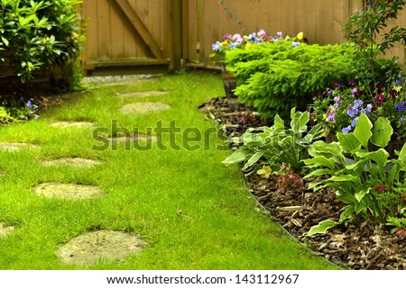 A beautifully landscaped back yard with stepping stones.