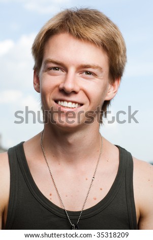 Portrait of a smiling young man on light blue sky background