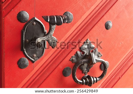 Vintage door handle on the red wooden door. Selective focus.