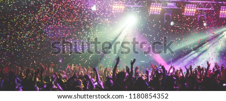 A crowded concert hall with scene stage lights, rock show performance, with people silhouette