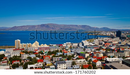 Beautiful Super Wide-Angle Aerial View Of Reykjavik, Iceland With Harbor And Skyline Mountains And Scenery Beyond The City, Seen From The Observation Tower Of Hallgrimskirkja Cathedral.