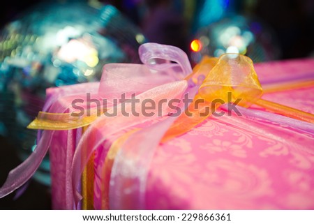 Elegantly wrapped new year christmas xmas birthday present in purple red pink box with a multicolored  ribbon with beautiful background bokeh
