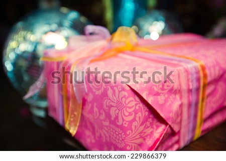 Elegantly wrapped new year christmas xmas birthday present in purple red pink box with a multicolored  ribbon with beautiful background bokeh