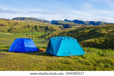 Campsite tents in Iceland - Summer camping with blue sky and mountains around.