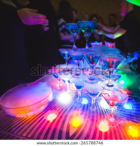Beautiful line of different colored cocktails with smoke on a open air party, tequila, martini, vodka, and others on decorated catering bouquet table on open air party with smoke