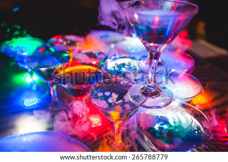 Beautiful line of different colored cocktails with smoke on a open air party, tequila, martini, vodka, and others on decorated catering bouquet table on open air party with smoke
