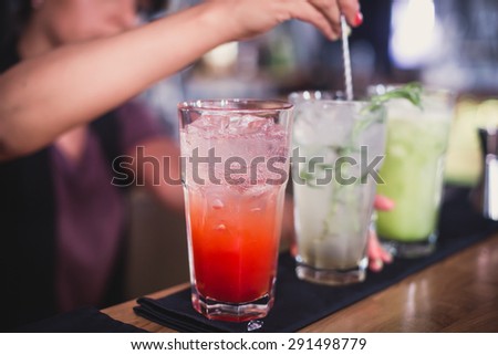 Beautiful line of red and different colored alcohol mojito cocktails with mint on a open air party, tequila, martini, vodka, and others on decorated catering bouquet table on open air event party